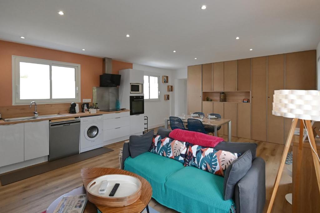 a living room with a couch and a kitchen at Sous le Marronnier - Maison pour 4 avec jardin in Royan