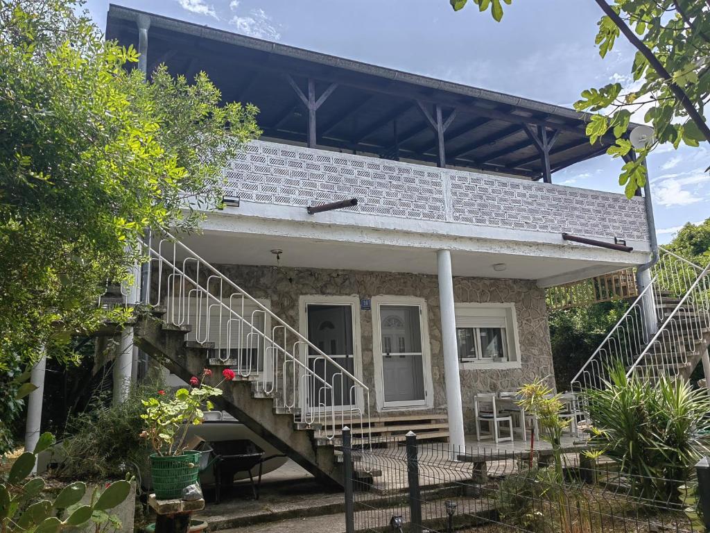 a brick house with a staircase in front of it at Vila Andja, Apartmani i Sobe in Krašići
