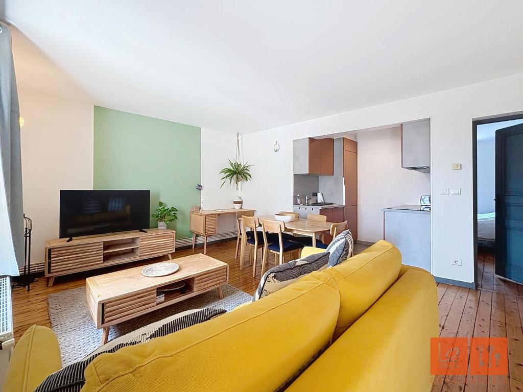 un salon avec un canapé jaune et une télévision dans l'établissement Les Hirondelles, à Wimereux