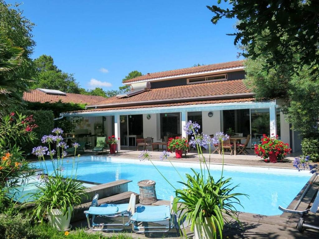 ein Swimmingpool mit Stühlen und ein Haus in der Unterkunft Villa Katy avec piscine, meublé de tourisme 3 étoiles in Andernos-les-Bains