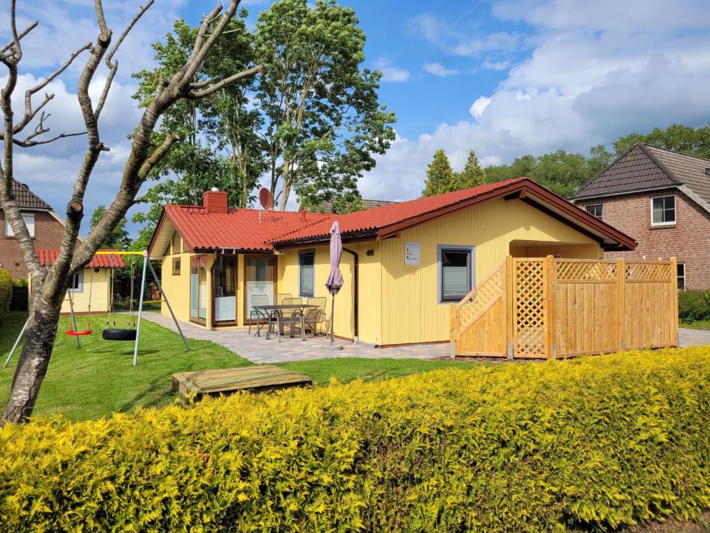 a yellow house with a red roof at Kinderfreundliches 6 Personen Ferienhaus mit zwei Duschen und Toiletten, Sauna, Whirlpool und einem Wintergarten mit Kaminofen in Otterndorf in Otterndorf