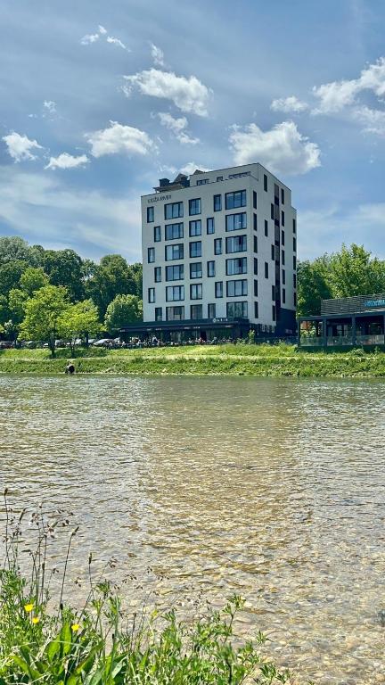 a large white building next to a body of water at Ilidza River Apartments in Sarajevo