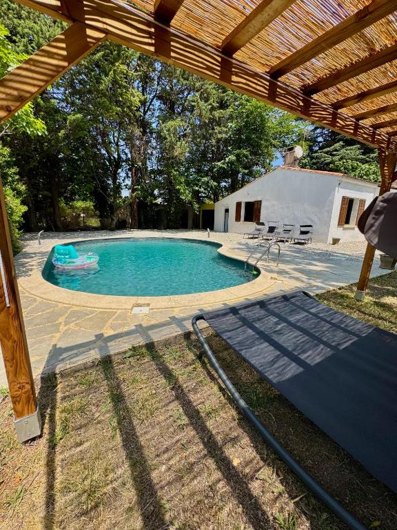 - une piscine dans une cour avec une pergola en bois dans l'établissement La maison vauclusienne, à Carpentras
