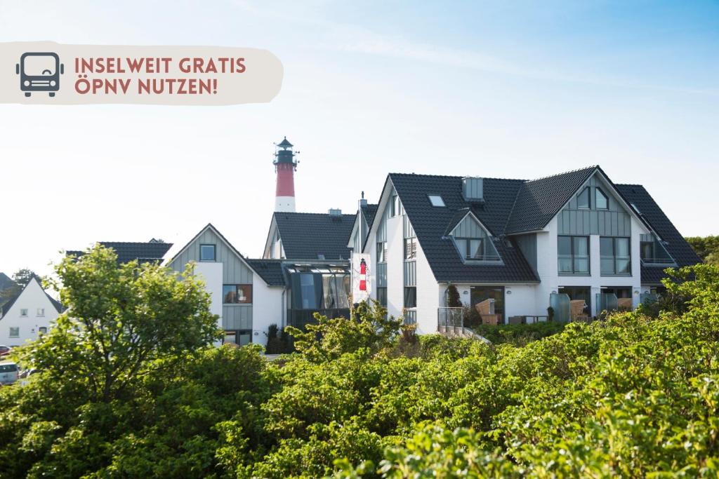 a house with a lighthouse in the background at Apartmenthotel am Leuchtturm in Hörnum