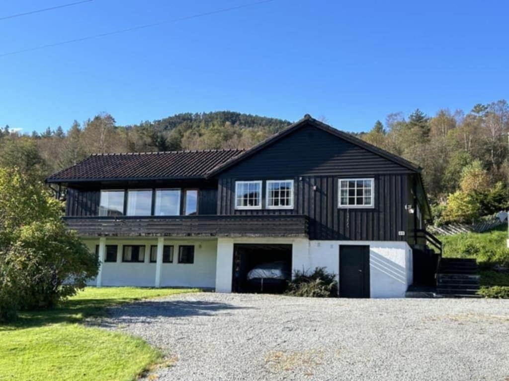 a black house with a garage and a driveway at Hus med stor hage ved Vatsfjorden in Åmsosen