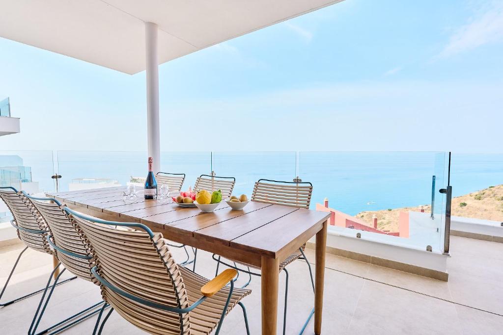 a dining table with chairs and a view of the ocean at IG01 Bayview Hills Torrox in Torrox