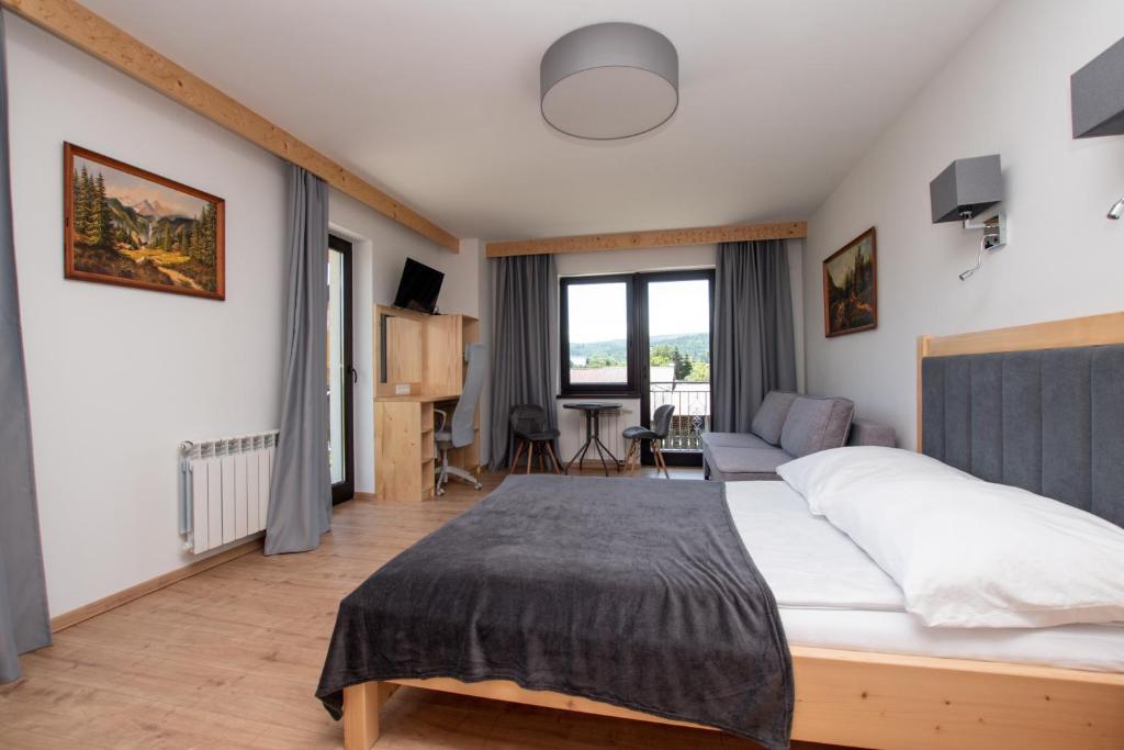 a bedroom with a bed and a living room at Pod Hawraniem pokoje z widokiem na Tatry Ski & Bike Friendly Jurgów in Jurgów