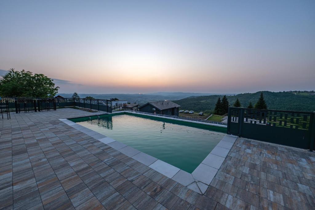 a swimming pool with the sunset in the background at Vila Natalijina Ramonda in Banja Luka