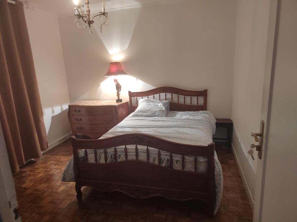 - une chambre avec un lit, une commode et une lampe dans l'établissement Villa B, à Bobigny