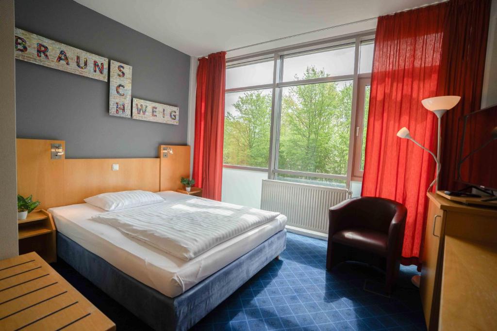 a bedroom with a bed and a large window at Plaza Inn Braunschweig City Nord in Braunschweig