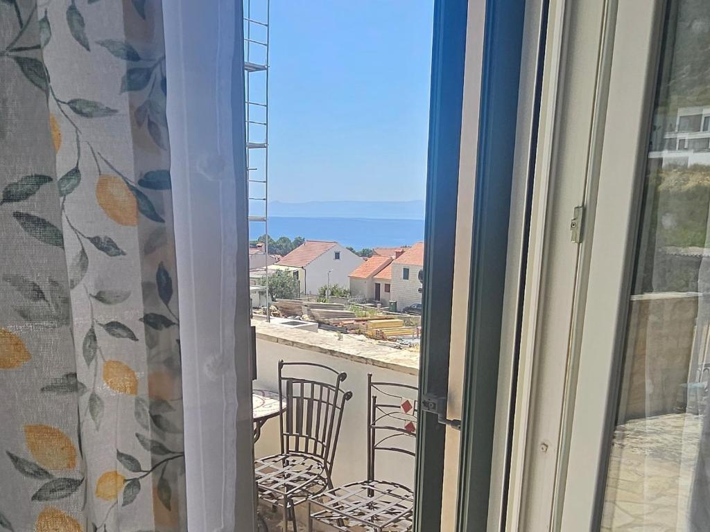a window with a view of a balcony with a table and chairs at Rooms Anđelka in Bol