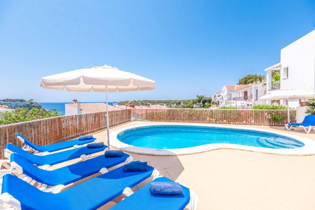 een zwembad met ligstoelen en een parasol bij Villa Carolina in Alaior