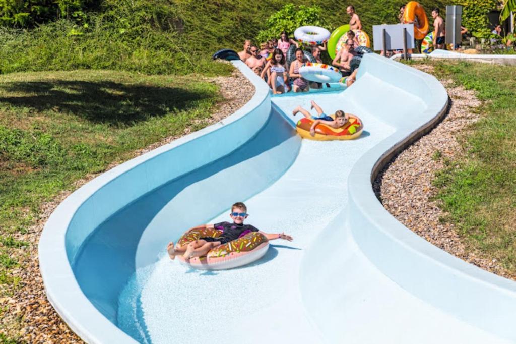 a group of people riding down a water slide at a water park at Camping Saint Avit Loisirs in Journiac