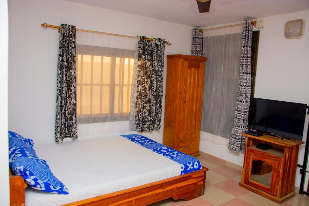 una camera da letto con un letto e una TV a schermo piatto di studio CHEZ VOUS a Lomé