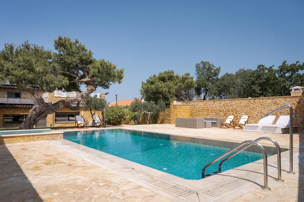 a swimming pool in a yard with chairs and trees at Aeolia Villa Athenian Riviera in Anavissos