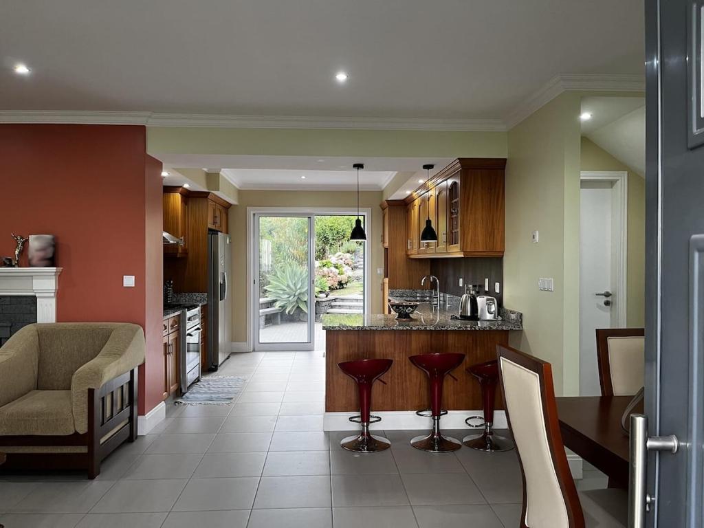 a kitchen with a bar with red stools at Casa da Ribeira - Azores in Ponta Garça