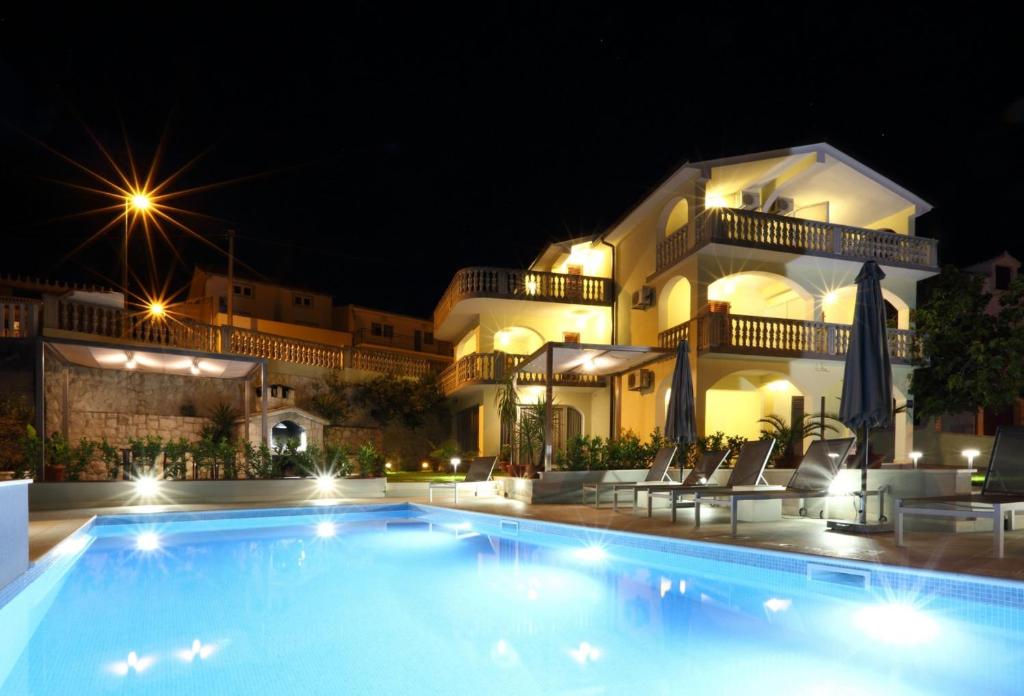 ein großer Pool vor einem Gebäude in der Nacht in der Unterkunft Apartments Bago in Trogir