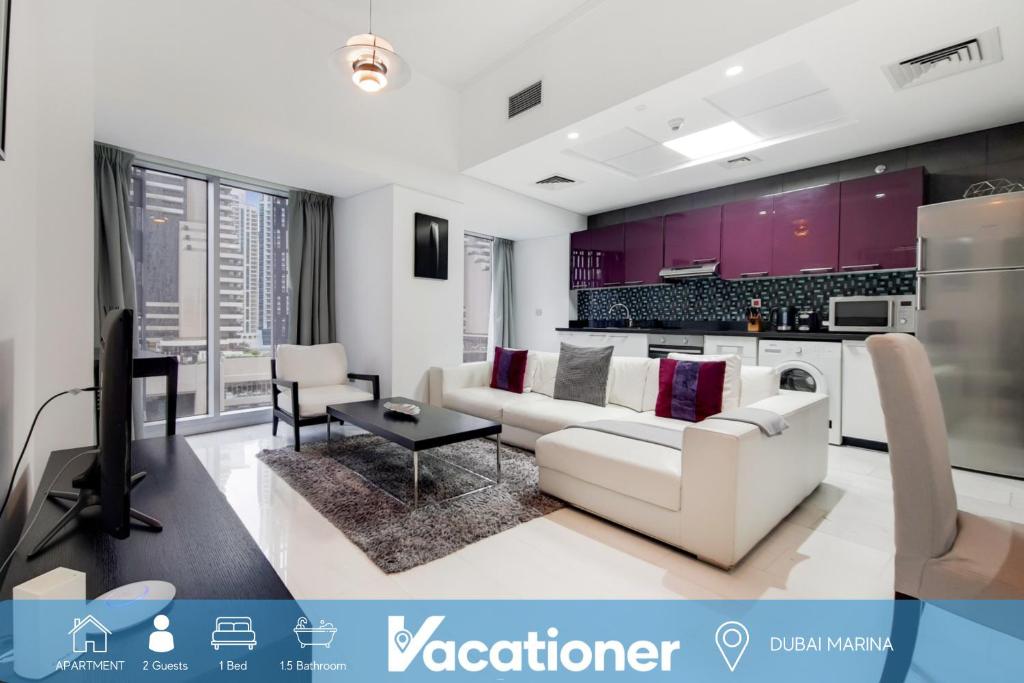 Una sala de estar con un sofá blanco y una cocina. en Cayan Tower, Dubai Marina - Charming One Bedroom, en Dubái