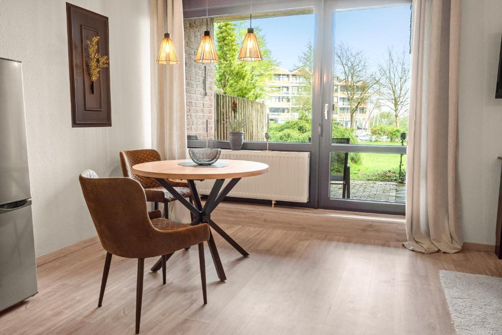 a dining room with a table and chairs and a window at Ankerplatz 2 - Hafenblick, Parkplatz, modern in Bad Zwischenahn