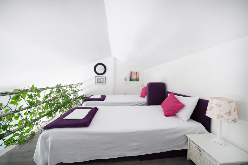 two beds in a room with white and pink pillows at The Tribunj Suites in Tribunj