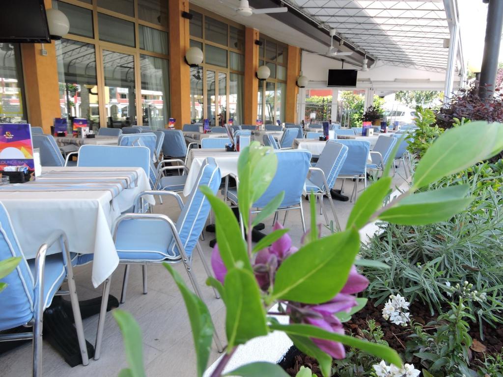 an empty restaurant with tables and chairs and flowers at Hotel Berna in Eraclea Mare