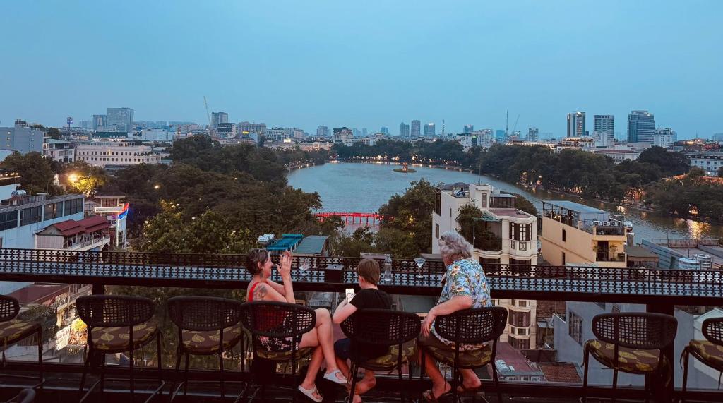 three women sitting on a balcony overlooking a river at Lucien Hanoi Lakeside Hotel & Rooftop in Hanoi