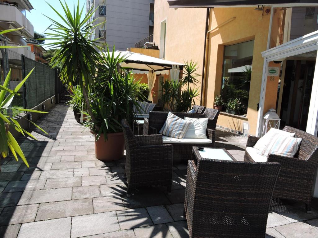 a patio with wicker chairs and tables and potted plants at Hotel Berna in Eraclea Mare