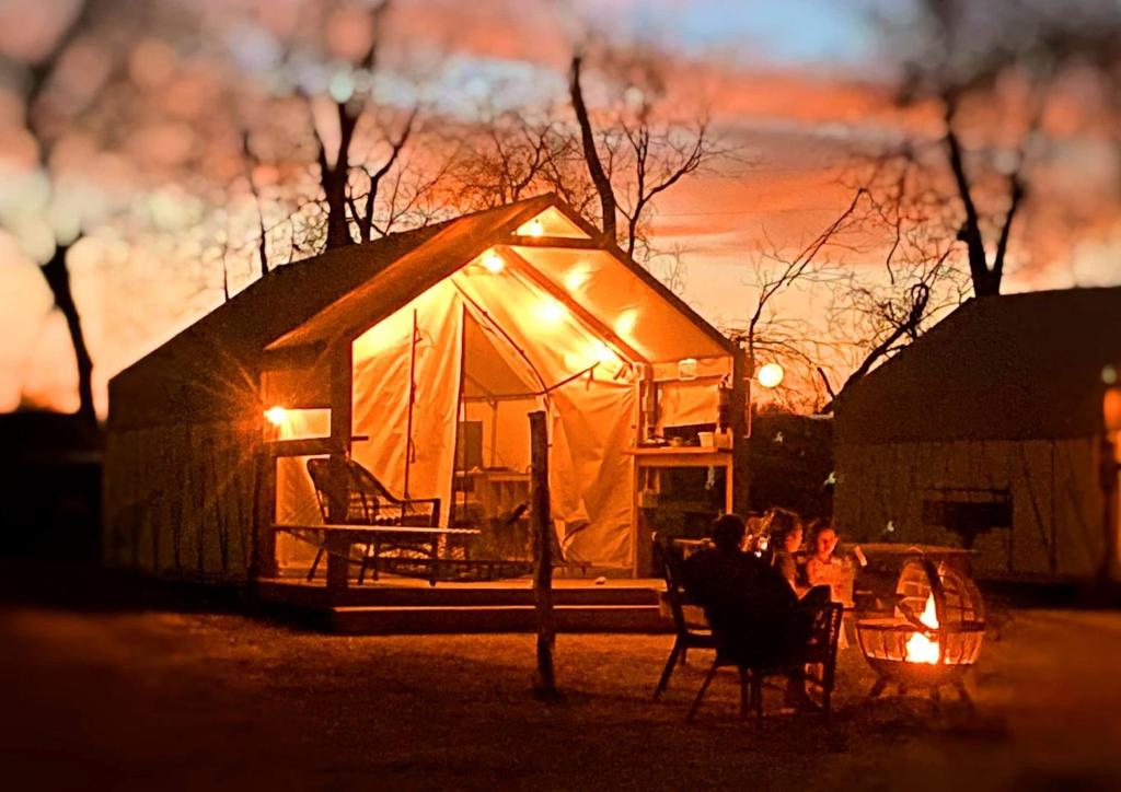 grupa ludzi siedzących w fotelach przed namiotem w obiekcie Luxury Safari Tent on the San Marcos River - Stunning Glamping Spot near Kingsbury, Texas w mieście Staples