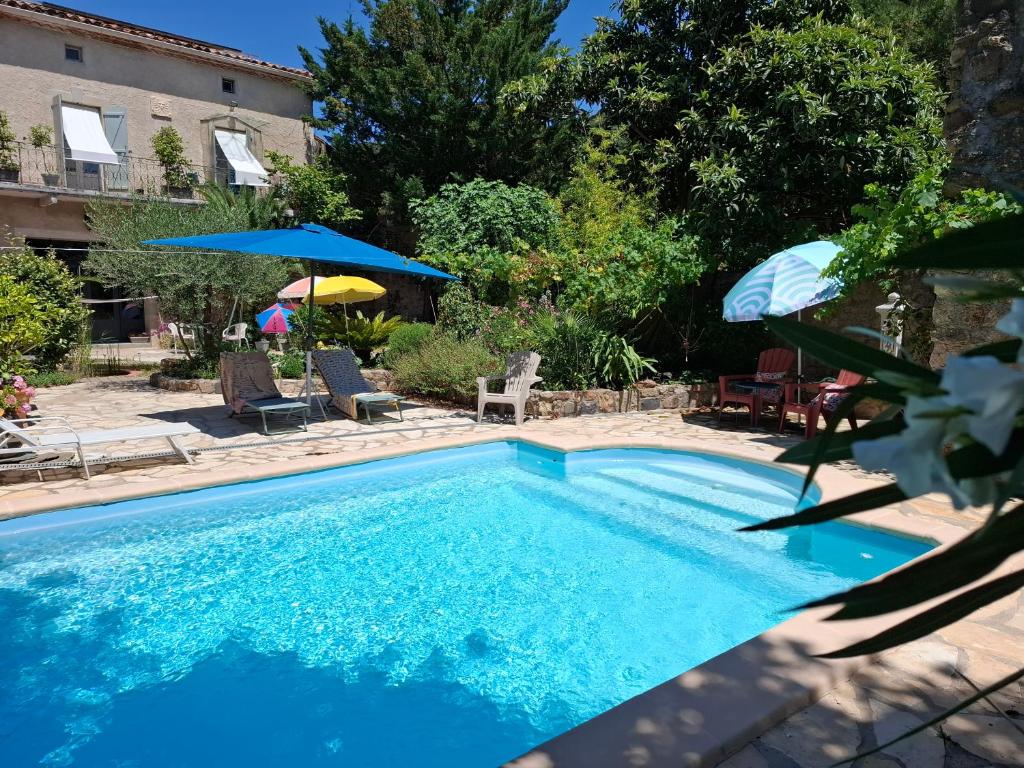 une piscine bleue avec des chaises et des parasols dans l'établissement Shanti Home, à La Tour-sur-Orb
