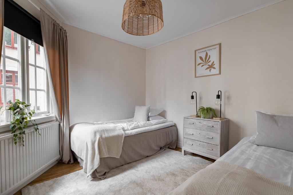 a white bedroom with two beds and a dresser at Cozy studio in separate building in Visby