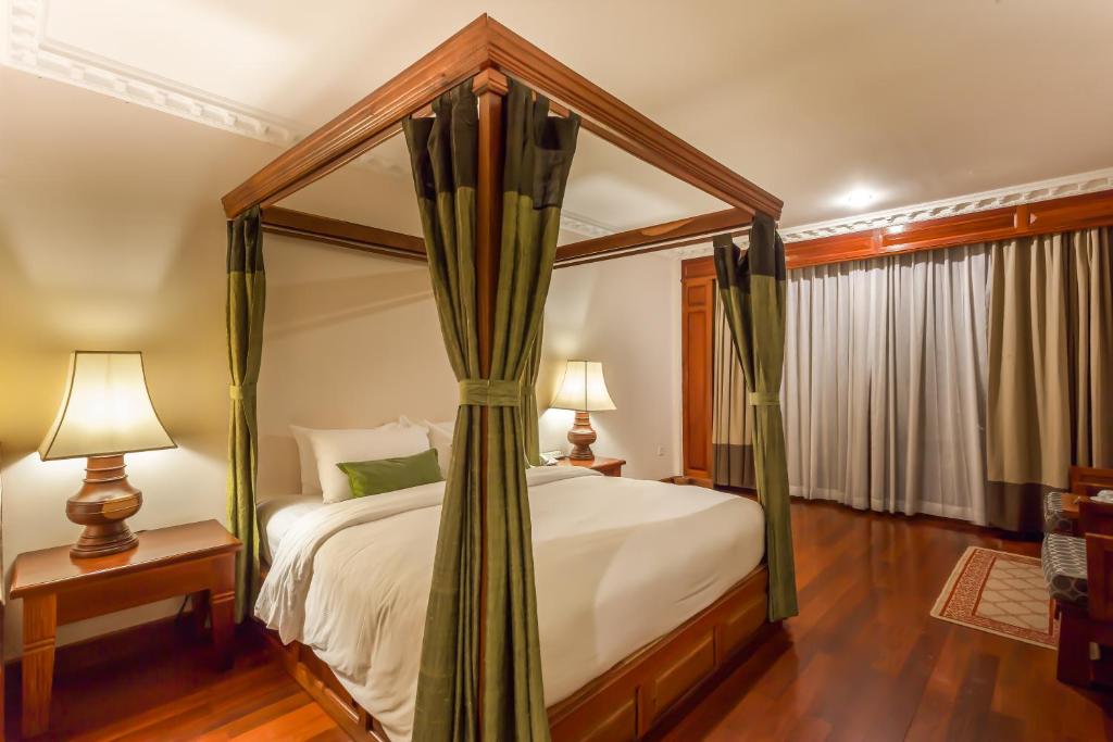 a bedroom with a four poster bed with a canopy at Prince Angkor Hotel & Spa in Siem Reap