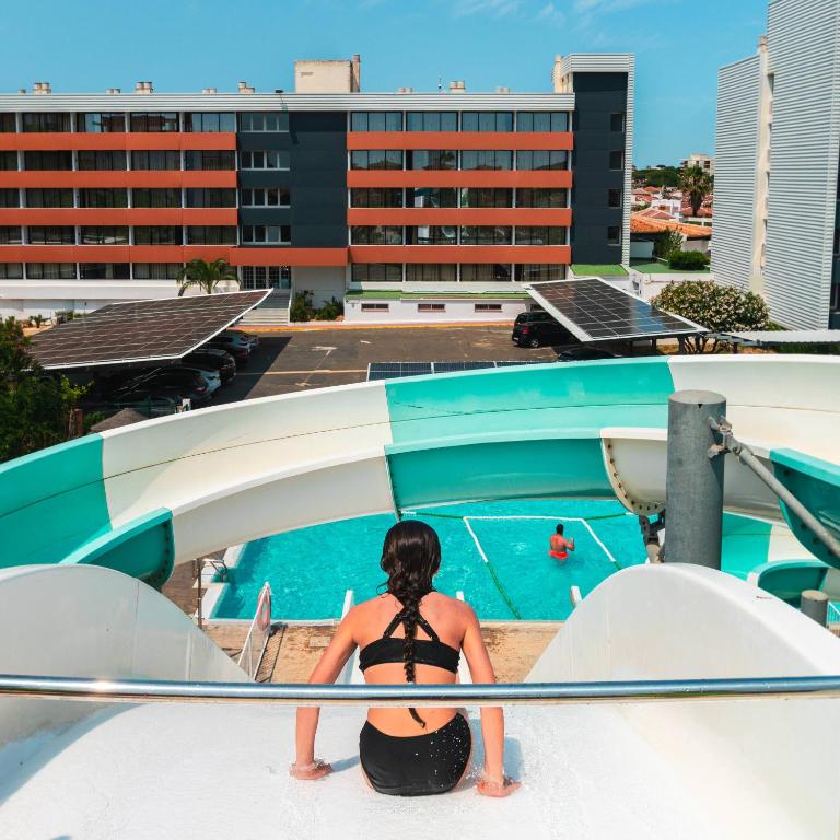 a woman sitting on the ledge of a swimming pool at Ohtels Carabela in Matalascañas