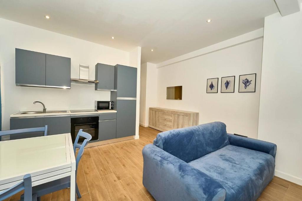 a living room with a blue couch and a kitchen at Allegra elegance homes in Nettuno