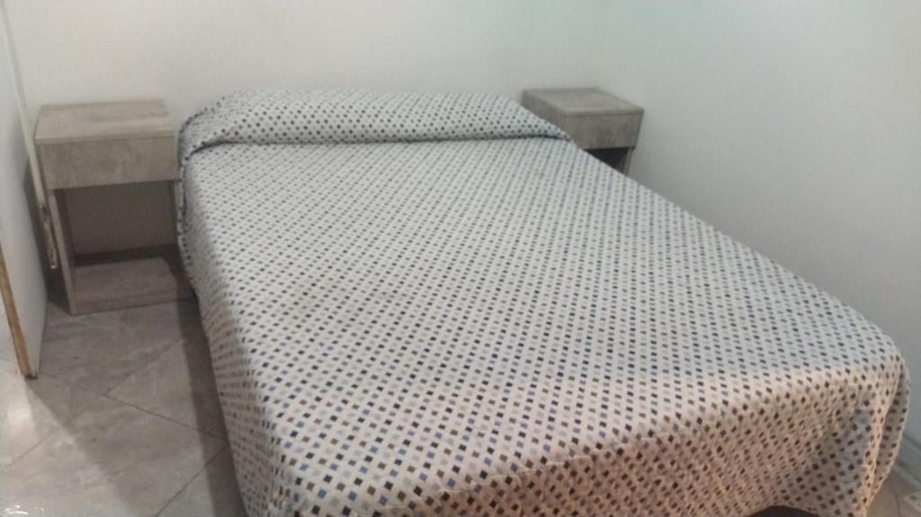a bed sitting in a room with two tables at Dpto 1 in San Justo