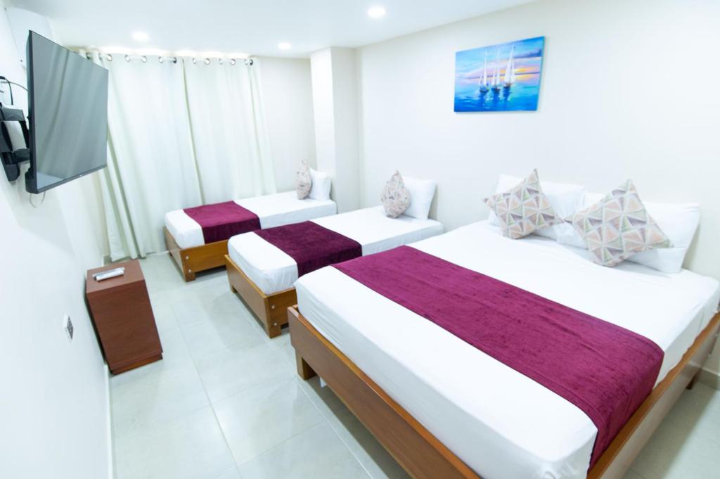a hotel room with two beds and a tv at hotel sierra nevada centro histórico in Santa Marta