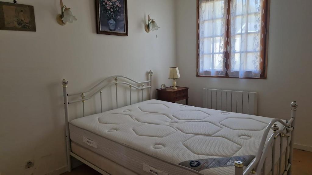 a white bed in a bedroom with a window at Le Jardin des Vignes in Montsoreau