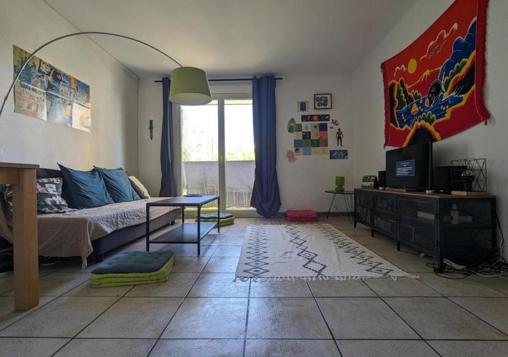 - un salon avec un lit, une table et une télévision dans l'établissement Le Nid de près d'arènes, à Montpellier