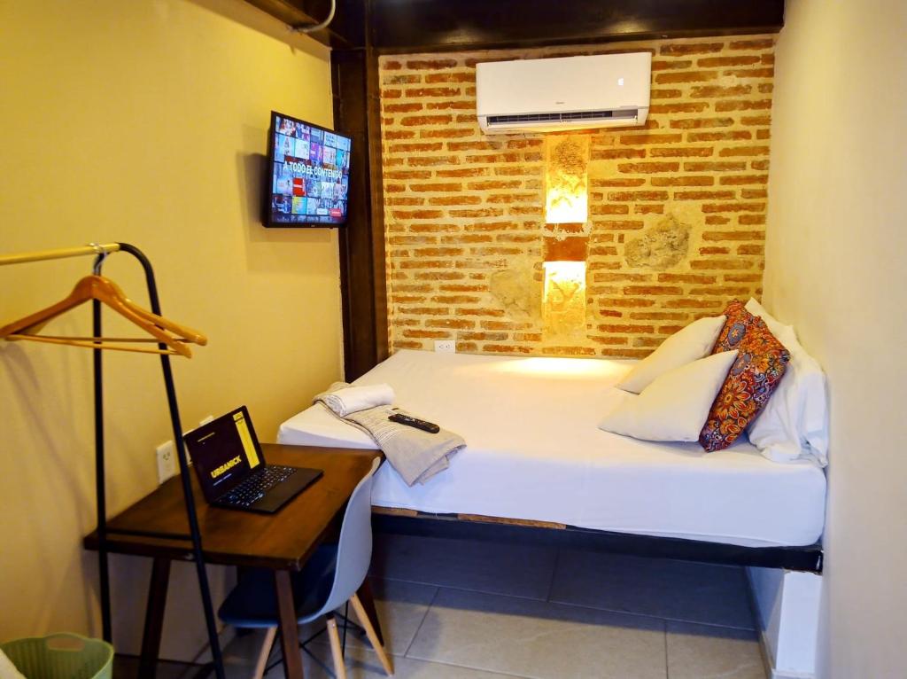 a room with a bed and a desk with a laptop at Habitación privada en Getsemaní in Cartagena de Indias