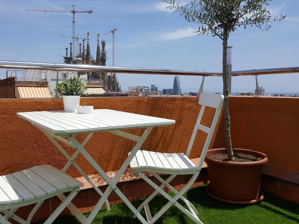バルセロナにあるYour Home in Barcelona Apartmentsの木のあるバルコニー(白いテーブルと椅子付)