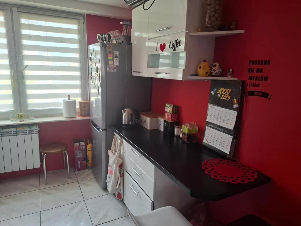 a kitchen with red walls and a black counter top at Pokoje do wynajęcia in Michałowo