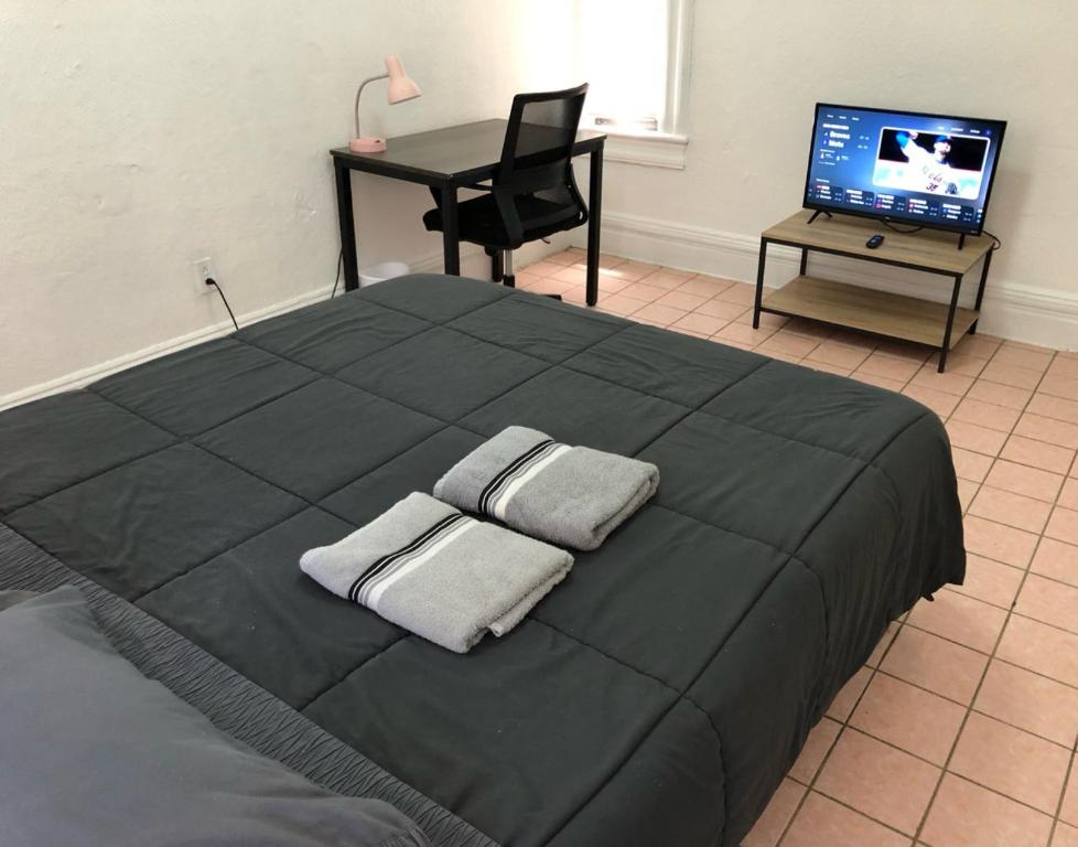 Private 2-bedroom apartment and New York City Manhattan only 15 mins away في يونيون سيتي: غرفة نوم بسرير أسود عليها منشفتين