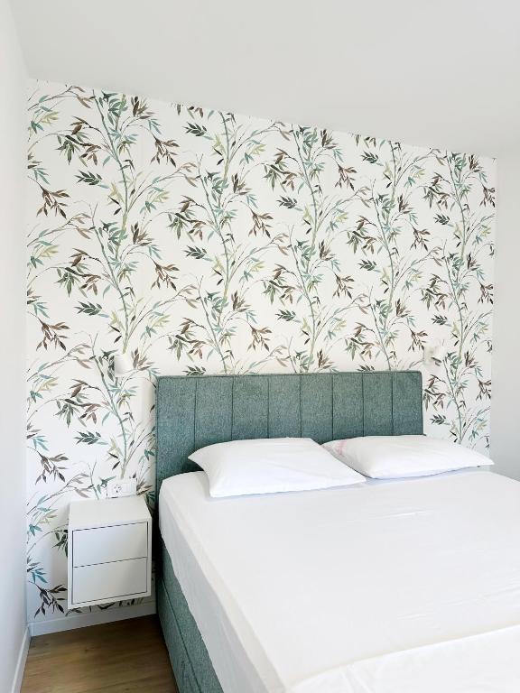 a bedroom with a bed and a wall with a floral wallpaper at Apartments Vinka in Jelsa