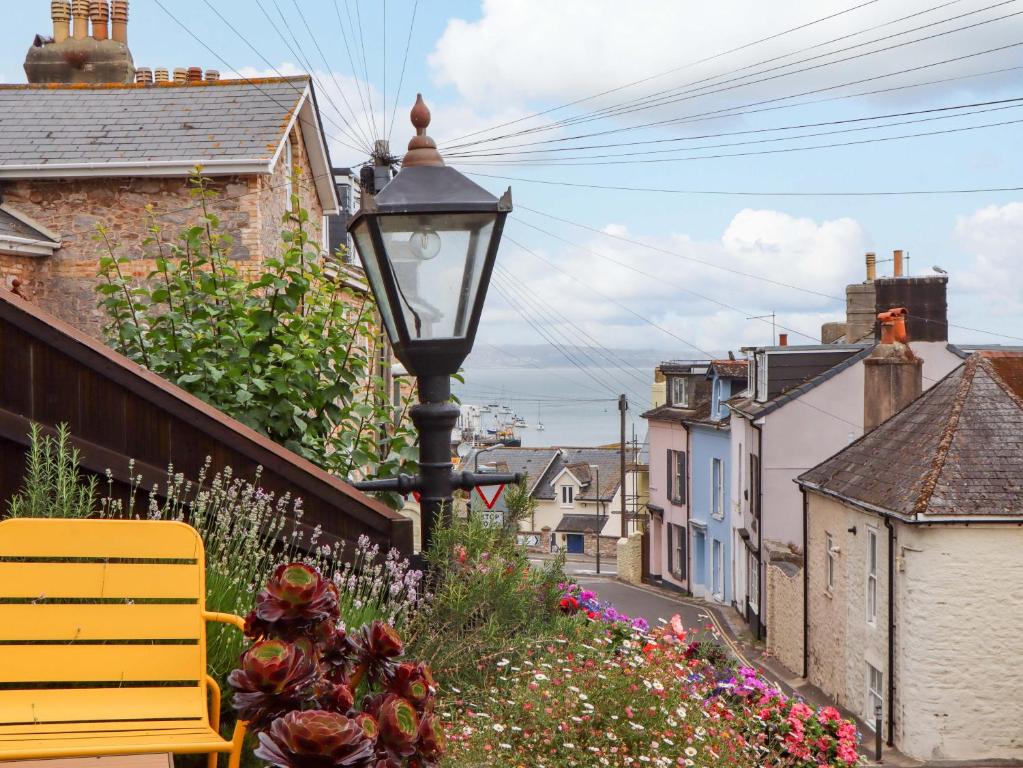 un banc jaune assis à côté d'un lampadaire dans l'établissement Captains Cottage, à Brixham