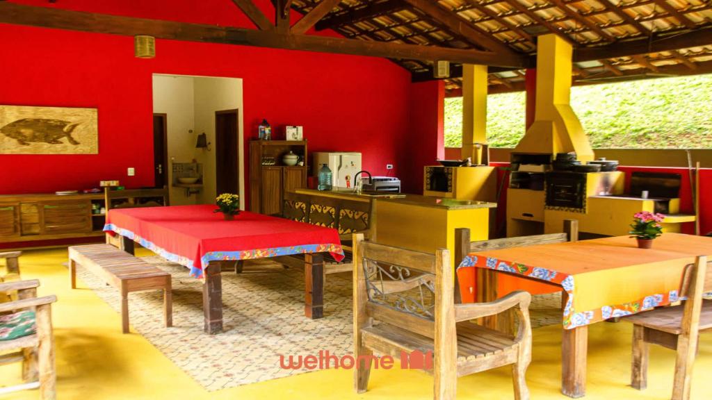 a kitchen with red walls and wooden tables and chairs at Suite em Sao Francisco Xavier com piscina in São Francisco Xavier