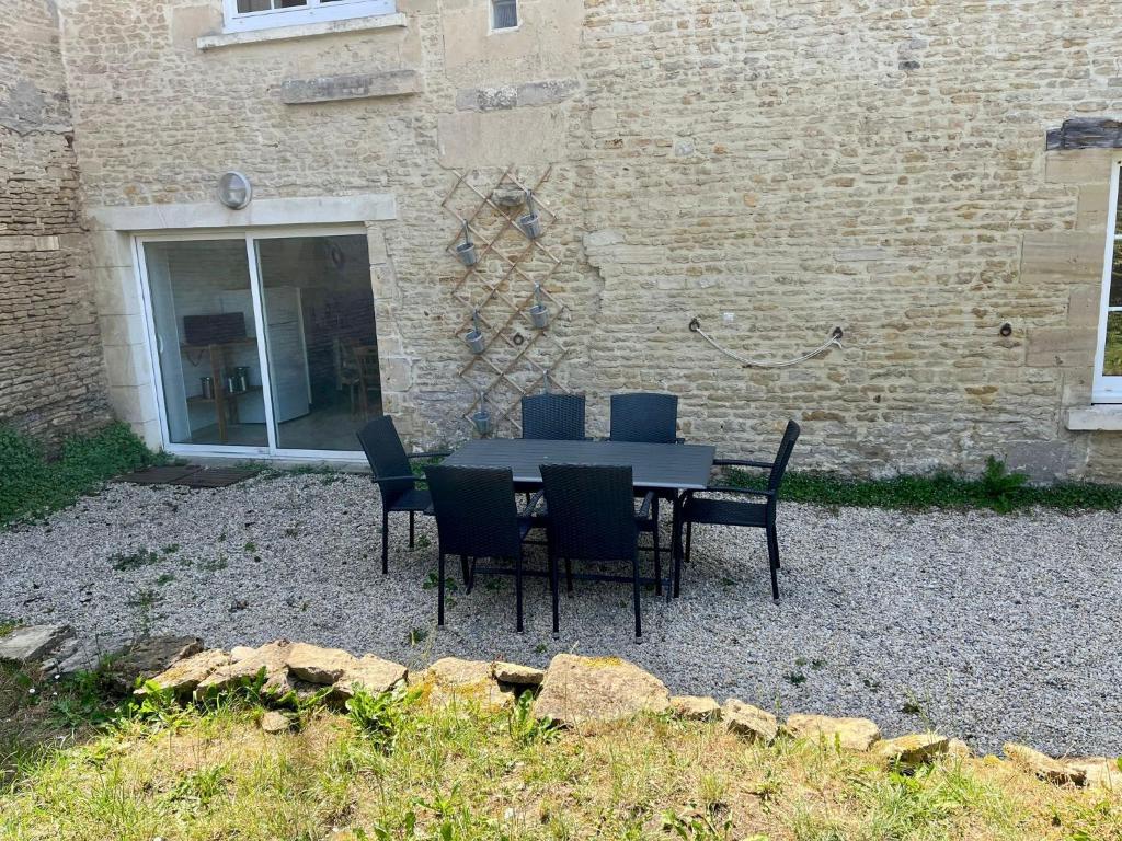 a black table and chairs in front of a building at La Belle des champs - maison avec terrasse in Courseulles-sur-Mer