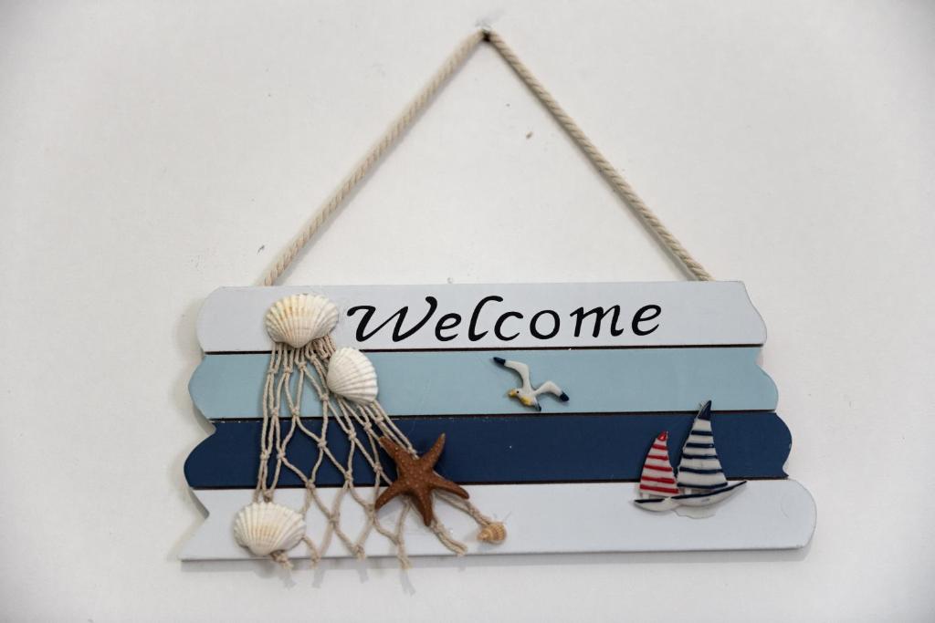 un cartello che dice benvenuto con conchiglie e un cartello che dice benvenuto di Villetta al mare a Marina di Mancaversa