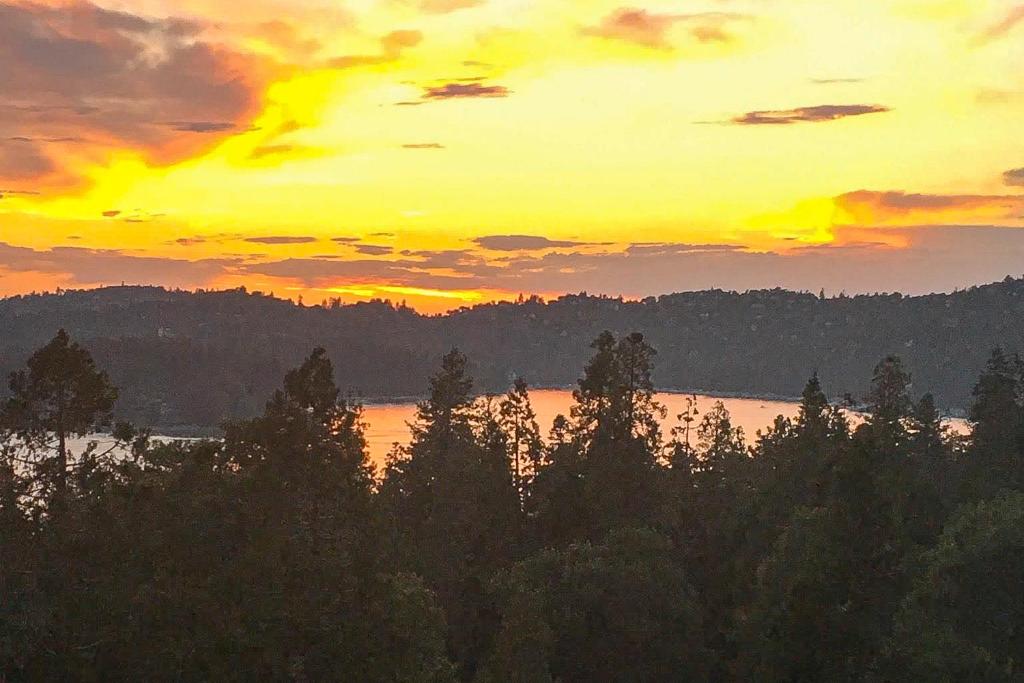 einen Sonnenuntergang über einem See mit Bäumen im Vordergrund in der Unterkunft Bright Moon in Lake Arrowhead