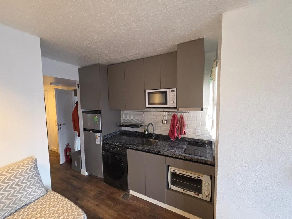 een kleine keuken met een spoelbak en een magnetron bij Recién renovado, 2 habitaciones, 1 baño in Las Lenas