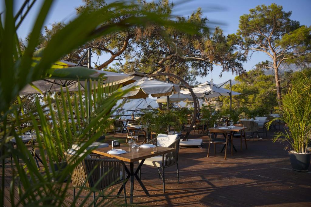 a restaurant with tables and chairs and umbrellas at Lov Faralya Adults Only in Faralya