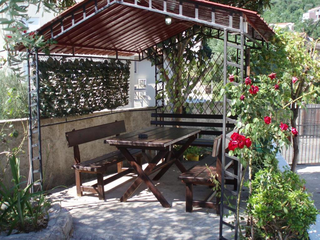 a picnic table and bench under a pergola with roses at M Group Studios in Tivat